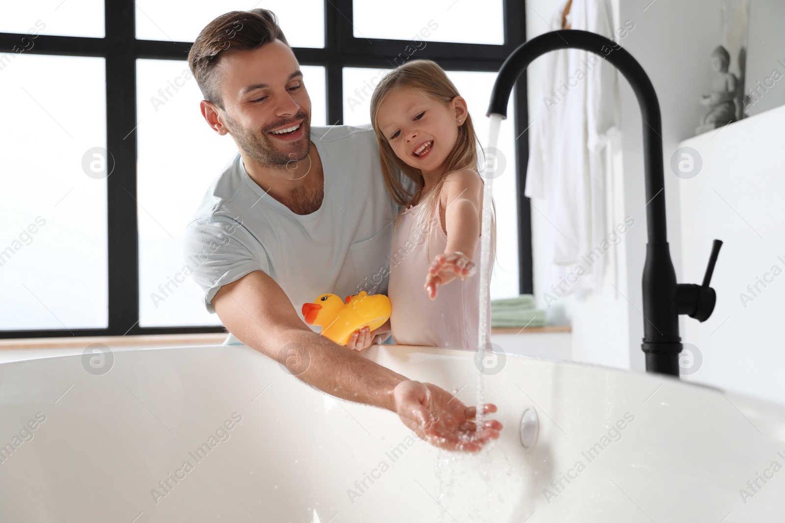 Father with his cute little daughter filling tub in bathroom Photo of Father with his cute little daughter filling tub in bathroom