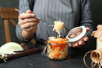 Woman eating fermented cabbage at black table, closeup Photo of Woman eating fermented cabbage at black table, closeup