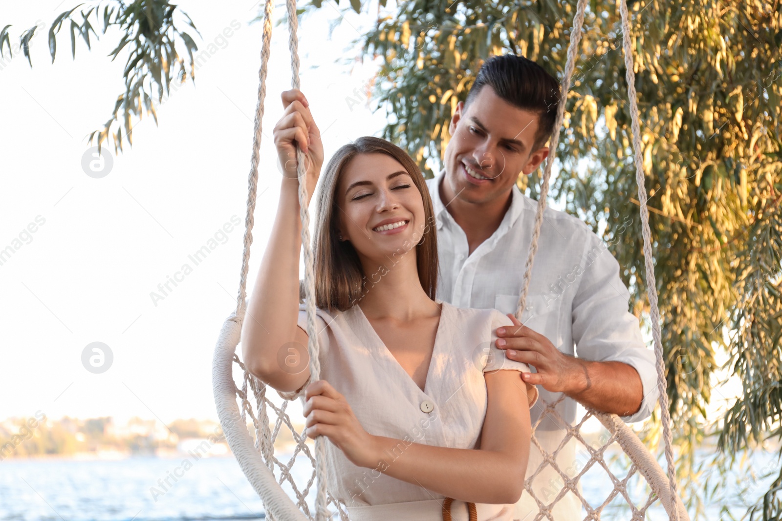Young woman in hammock chair and her boyfriend on beach. Summer vacation Photo of Young woman in hammock chair and her boyfriend on beach. Summer vacation