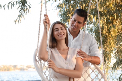 Young woman in hammock chair and her boyfriend on beach. Summer vacation Photo of Young woman in hammock chair and her boyfriend on beach. Summer vacation