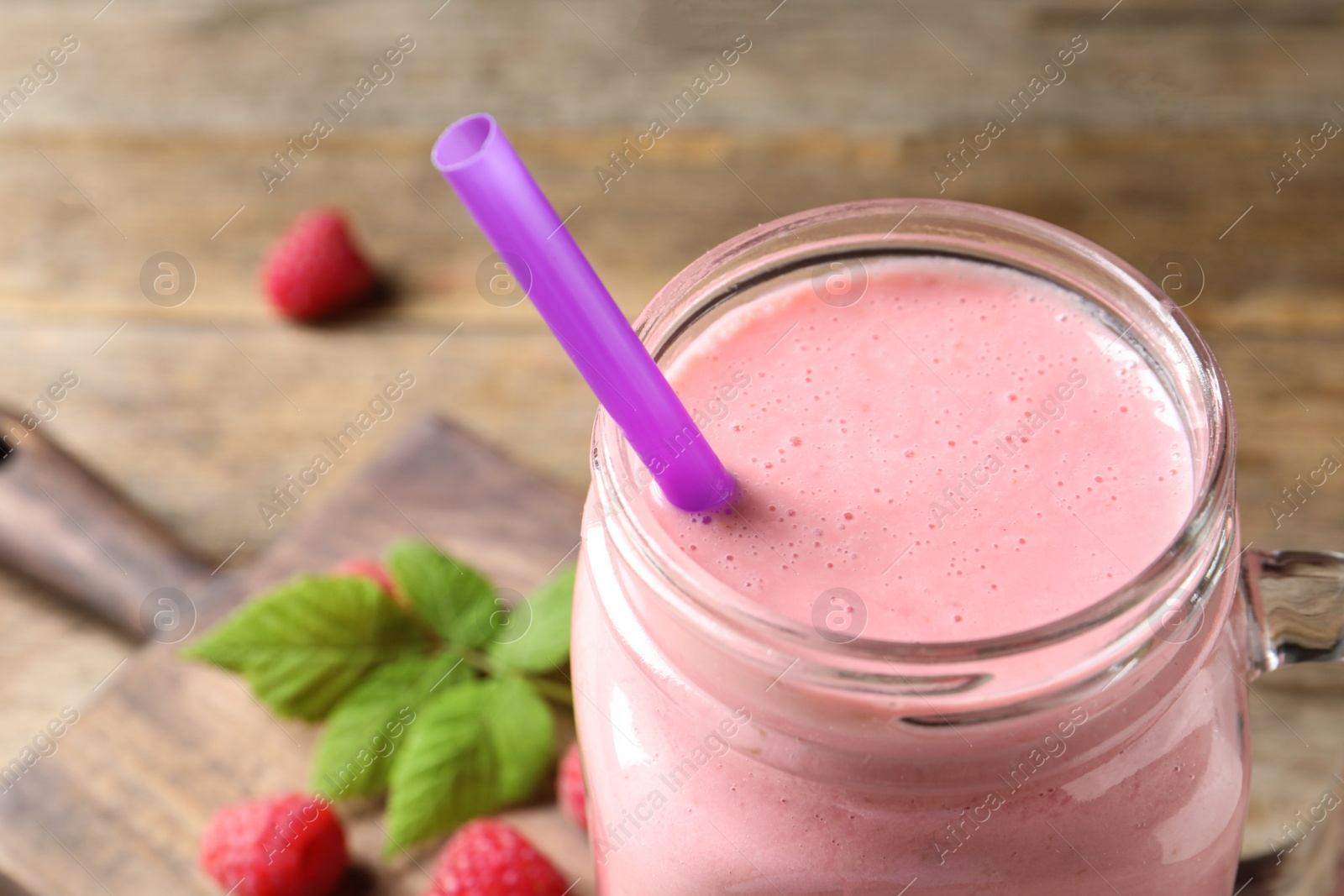 Yummy raspberry smoothie in mason jar on wooden table, closeup Image of Yummy raspberry smoothie in mason jar on wooden table, closeup