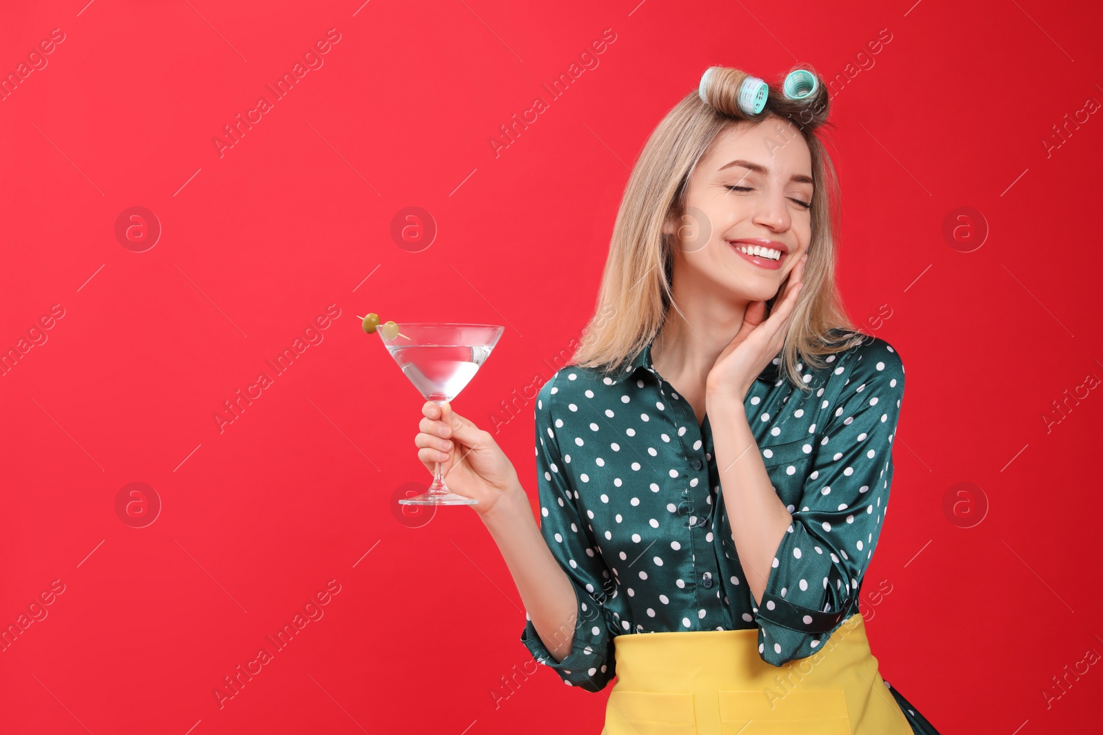 Young housewife with glass of martini on red background. Space for text Photo of Young housewife with glass of martini on red background. Space for text