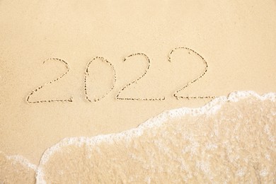 Sandy beach with written 2022 washed by sea. Happy New Year, above view Photo of Sandy beach with written 2022 washed by sea. Happy New Year, above view