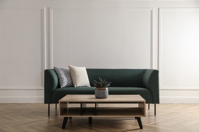 Stylish living room interior with comfortable green sofa and wooden table Photo of Stylish living room interior with comfortable green sofa and wooden table