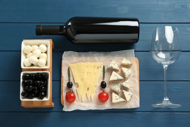 Tasty red wine and snacks on blue wooden table, flat lay Photo of Tasty red wine and snacks on blue wooden table, flat lay