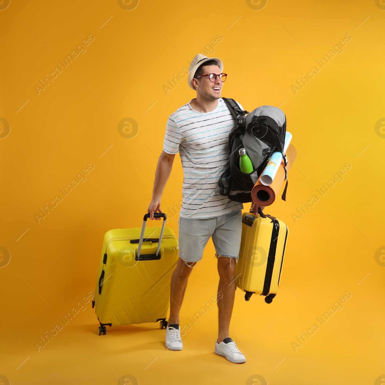 Male tourist with travel backpack and suitcases on yellow background Photo of Male tourist with travel backpack and suitcases on yellow background