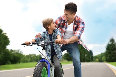 Dad teaching son to ride bicycle outdoors Image of Dad teaching son to ride bicycle outdoors