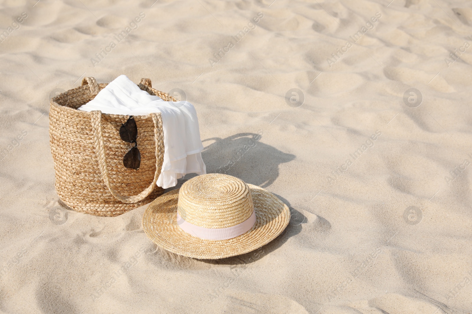 Beach bag, towel, sunglasses and hat on sand, space for text Photo of Beach bag, towel, sunglasses and hat on sand, space for text