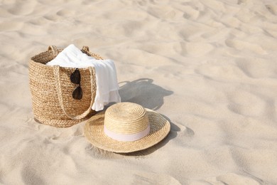 Beach bag, towel, sunglasses and hat on sand, space for text Photo of Beach bag, towel, sunglasses and hat on sand, space for text