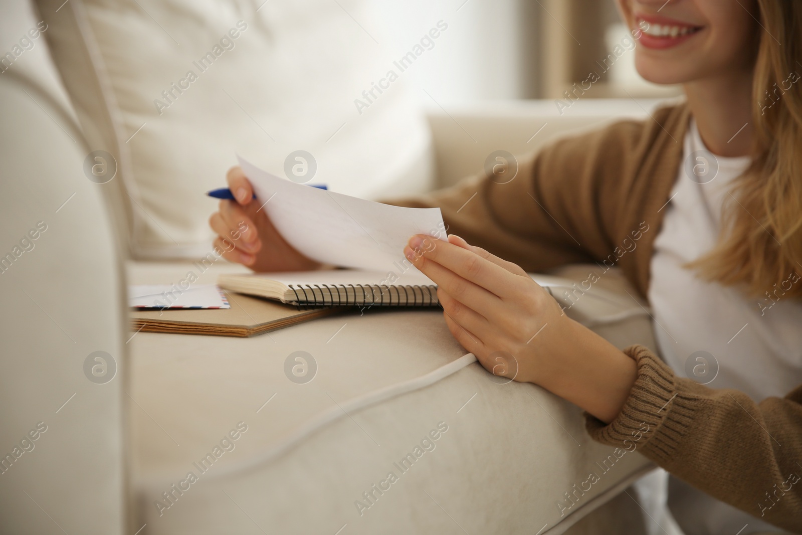 Happy woman writing letter on sofa at home, closeup Photo of Happy woman writing letter on sofa at home, closeup