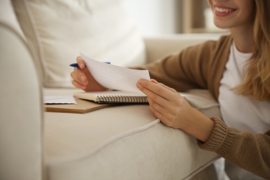 Happy woman writing letter on sofa at home, closeup Photo of Happy woman writing letter on sofa at home, closeup