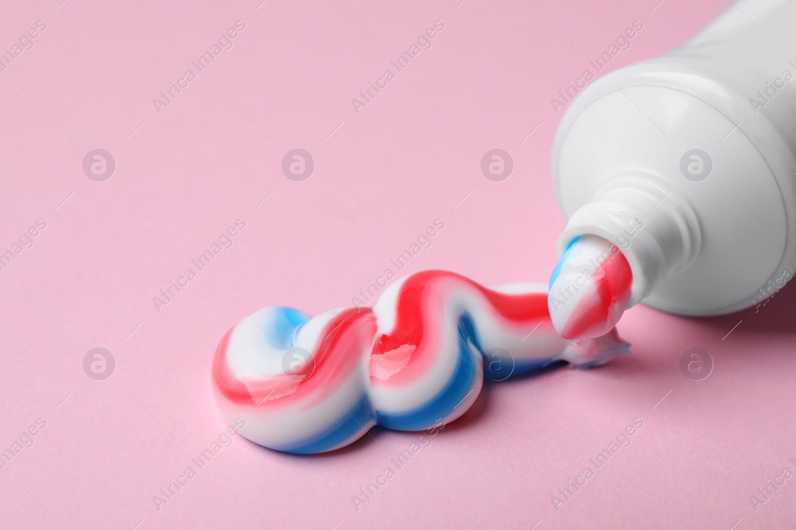Tube with squeezed out toothpaste on pink background, closeup Photo of Tube with squeezed out toothpaste on pink background, closeup