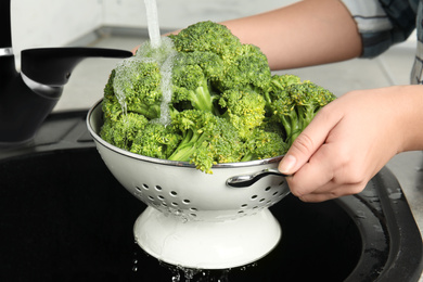 Woman washing fresh green broccoli in kitchen sink, closeup Photo of Woman washing fresh green broccoli in kitchen sink, closeup