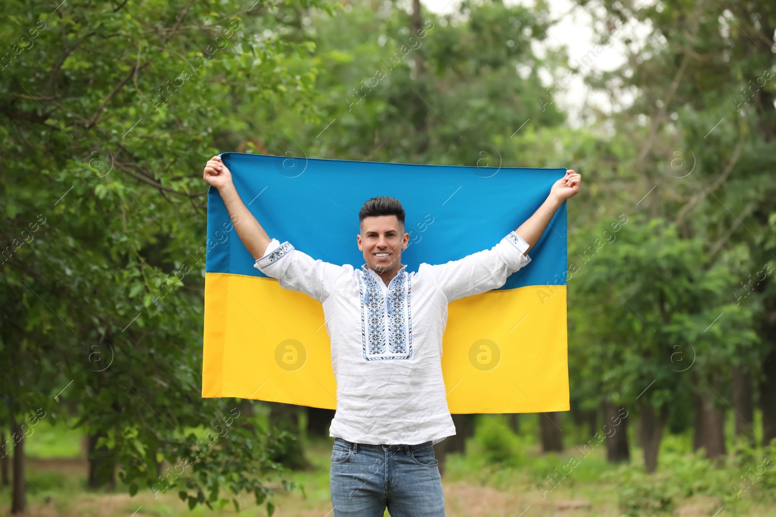 Man in vyshyvanka with flag of Ukraine outdoors Photo of Man in vyshyvanka with flag of Ukraine outdoors