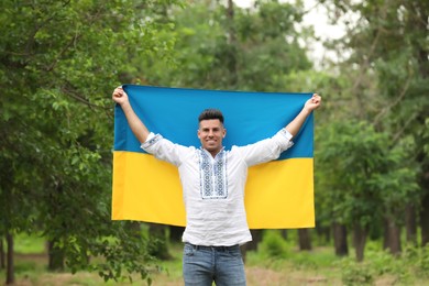 Man in vyshyvanka with flag of Ukraine outdoors Photo of Man in vyshyvanka with flag of Ukraine outdoors