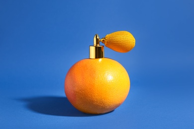 Grapefruit with vintage atomizer imitating perfume on blue background Photo of Grapefruit with vintage atomizer imitating perfume on blue background