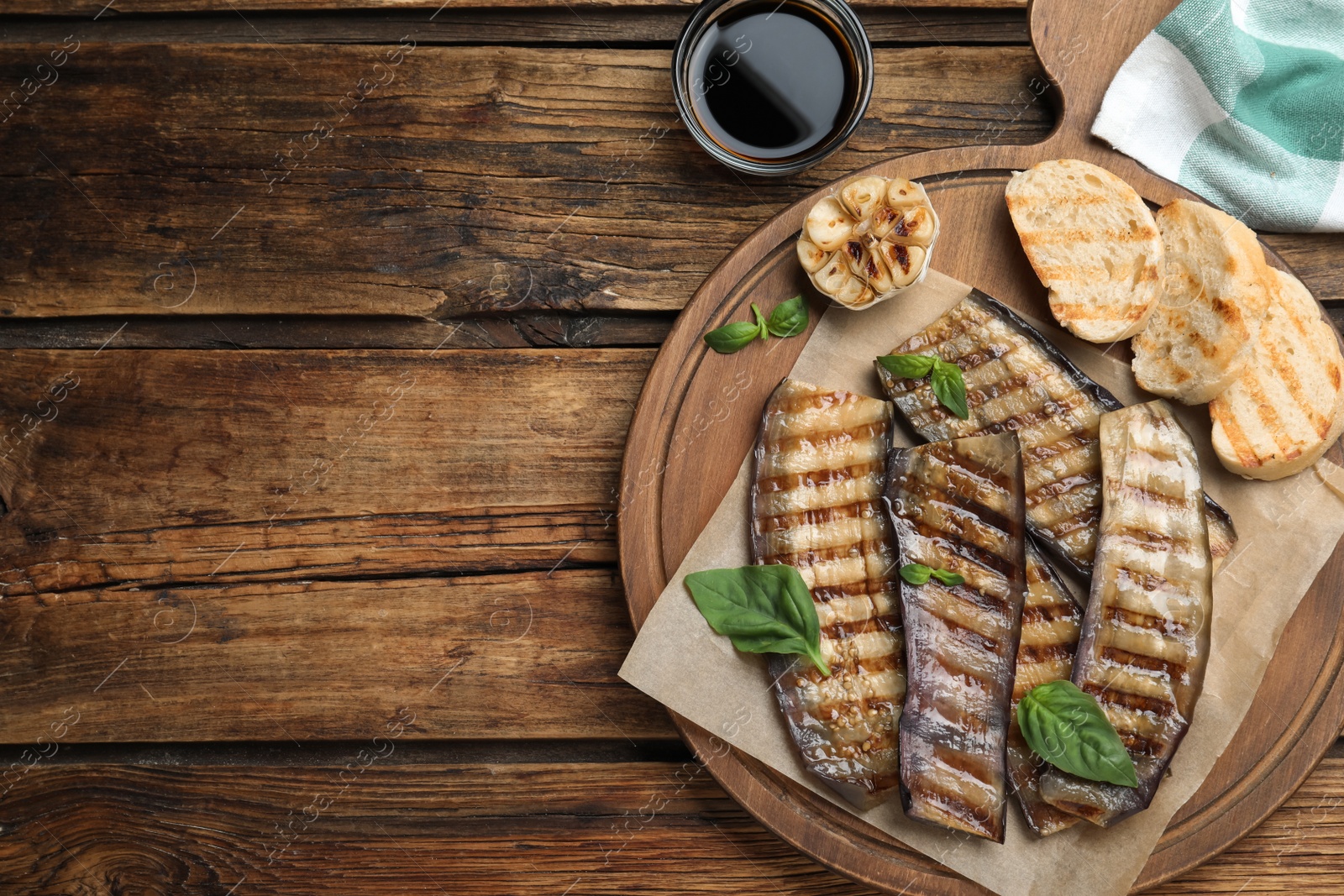 Delicious grilled eggplant slices served on wooden table, flat lay. Space for text Photo of Delicious grilled eggplant slices served on wooden table, flat lay. Space for text