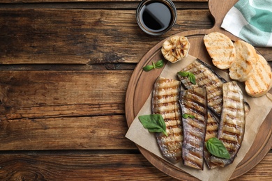 Delicious grilled eggplant slices served on wooden table, flat lay. Space for text Photo of Delicious grilled eggplant slices served on wooden table, flat lay. Space for text