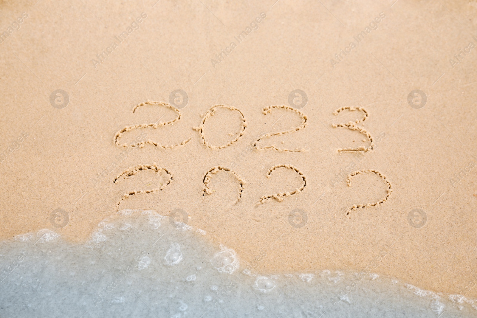 Dates written on sandy beach. 2022 washed by sea wave as New 2023 Year coming Photo of Dates written on sandy beach. 2022 washed by sea wave as New 2023 Year coming