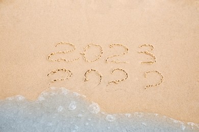 Dates written on sandy beach. 2022 washed by sea wave as New 2023 Year coming Photo of Dates written on sandy beach. 2022 washed by sea wave as New 2023 Year coming