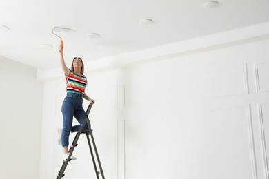 Young woman painting ceiling with white dye indoors, space for text Photo of Young woman painting ceiling with white dye indoors, space for text