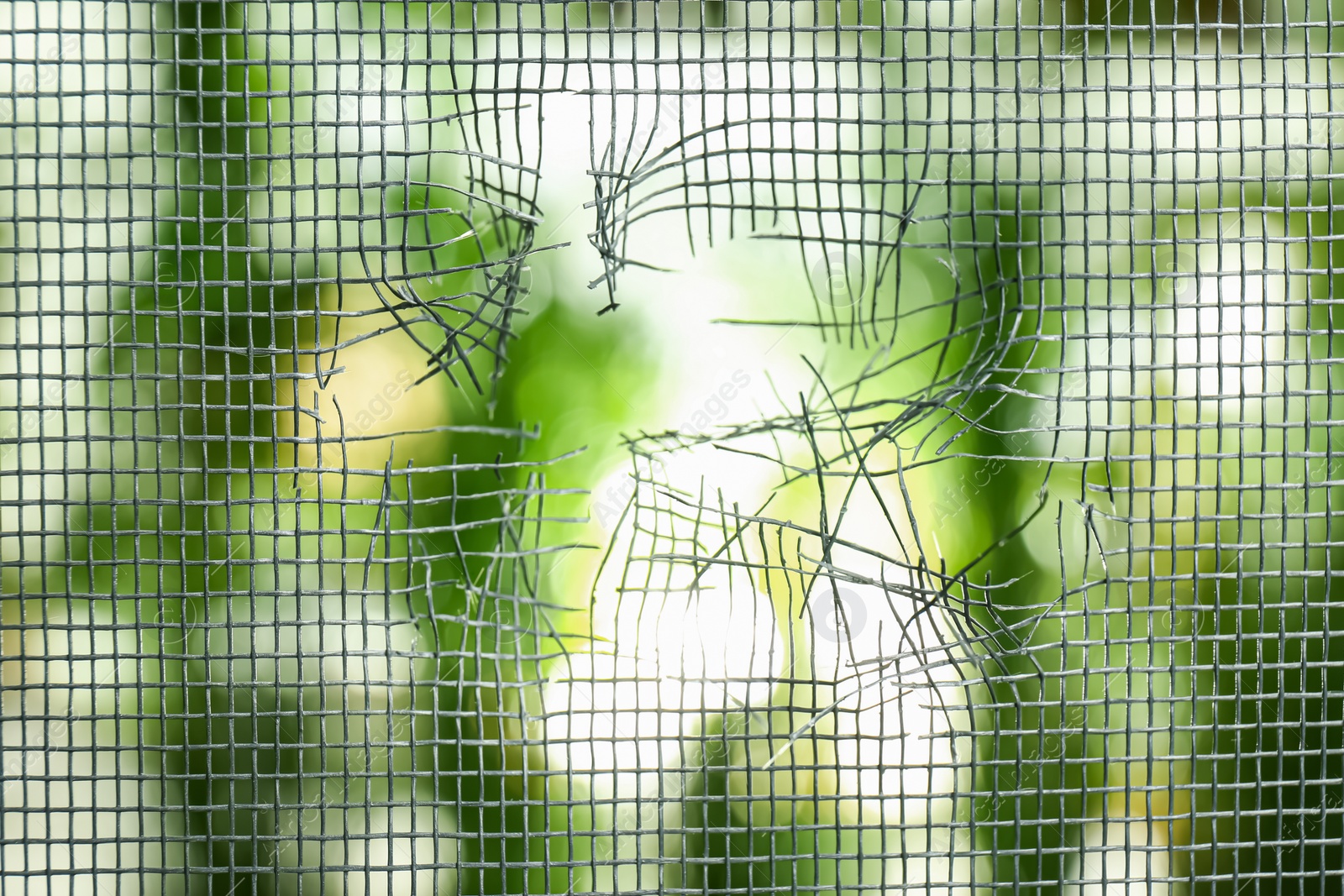 Torn window screen against blurred background, closeup Photo of Torn window screen against blurred background, closeup