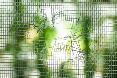 Torn window screen against blurred background, closeup Photo of Torn window screen against blurred background, closeup