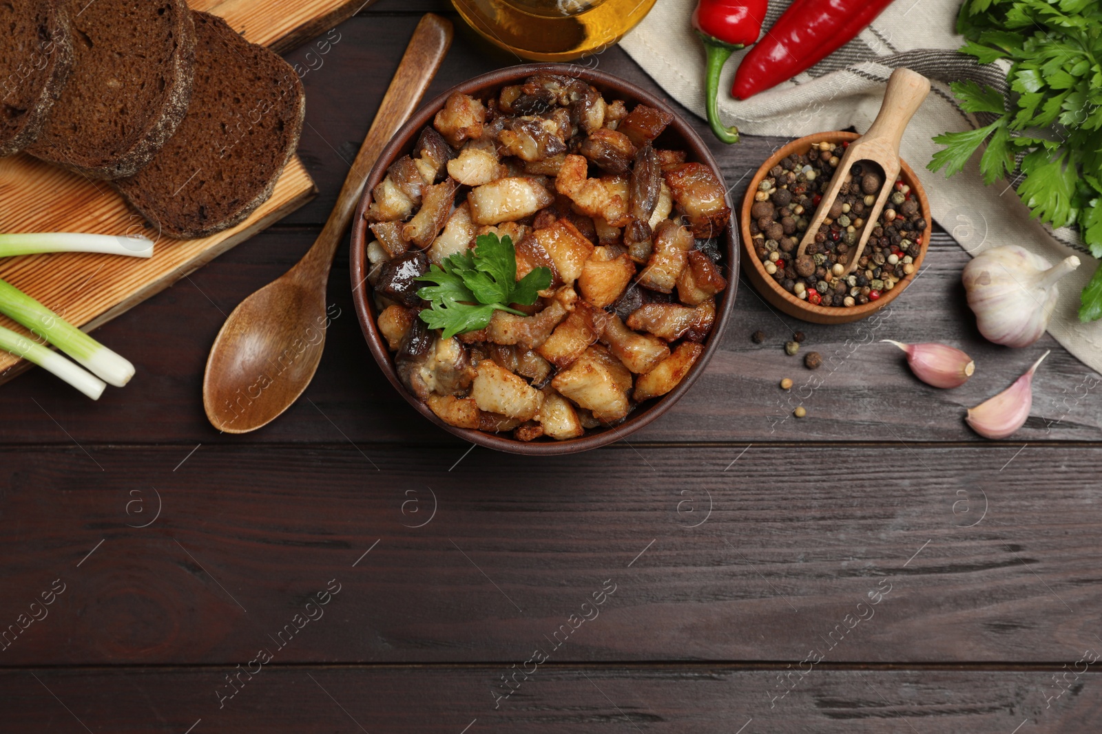 Tasty fried cracklings and different ingredients on wooden table, flat lay with space for text. Cooked pork lard Photo of Tasty fried cracklings and different ingredients on wooden table, flat lay with space for text. Cooked pork lard
