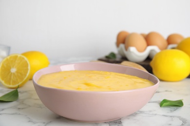 Photo of Delicious lemon curd on white marble table
