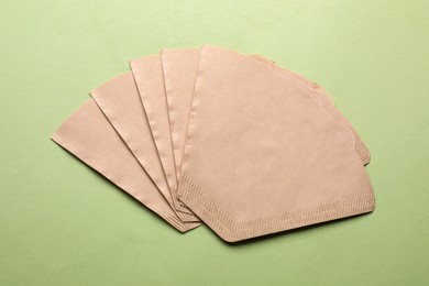 Paper coffee filters on pale olive background, flat lay Photo of Paper coffee filters on pale olive background, flat lay