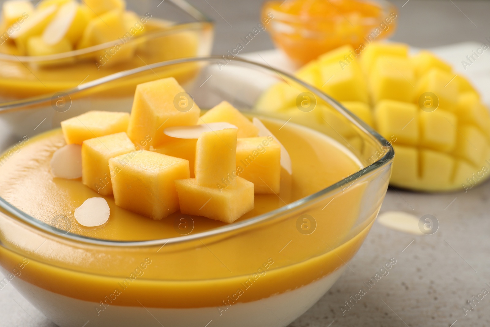 Delicious panna cotta with mango coulis and fresh fruit pieces on grey table, closeup Photo of Delicious panna cotta with mango coulis and fresh fruit pieces on grey table, closeup
