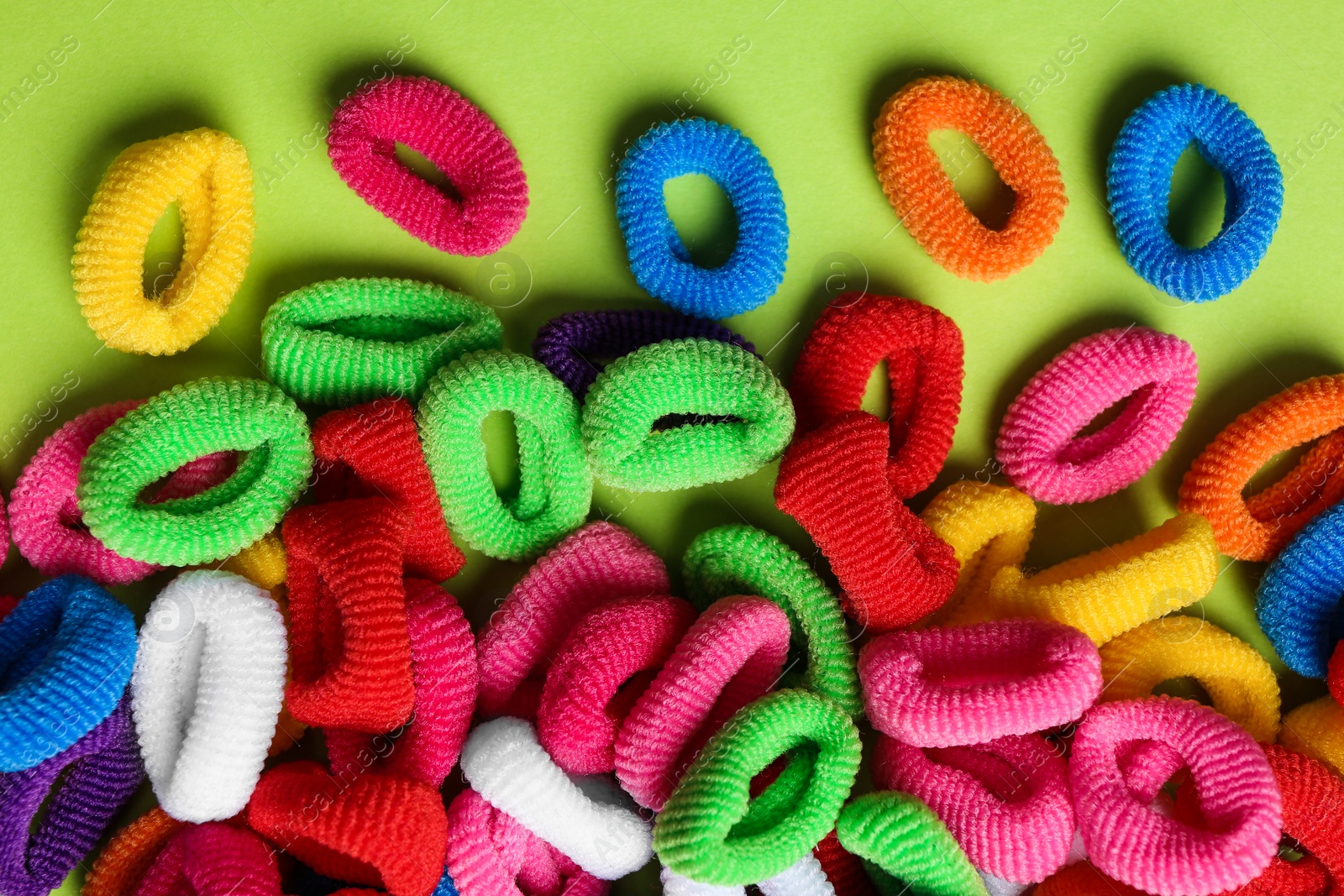 Different colorful hair ties on light green background, flat lay Photo of Different colorful hair ties on light green background, flat lay