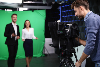 Presenters and video camera operator working in studio. News broadcasting Photo of Presenters and video camera operator working in studio. News broadcasting