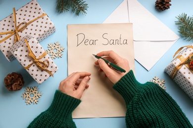 Top view of woman writing letter to Santa at light blue table, closeup Photo of Top view of woman writing letter to Santa at light blue table, closeup