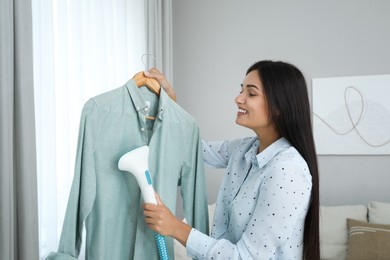 Woman steaming shirt on hanger at home Photo of Woman steaming shirt on hanger at home