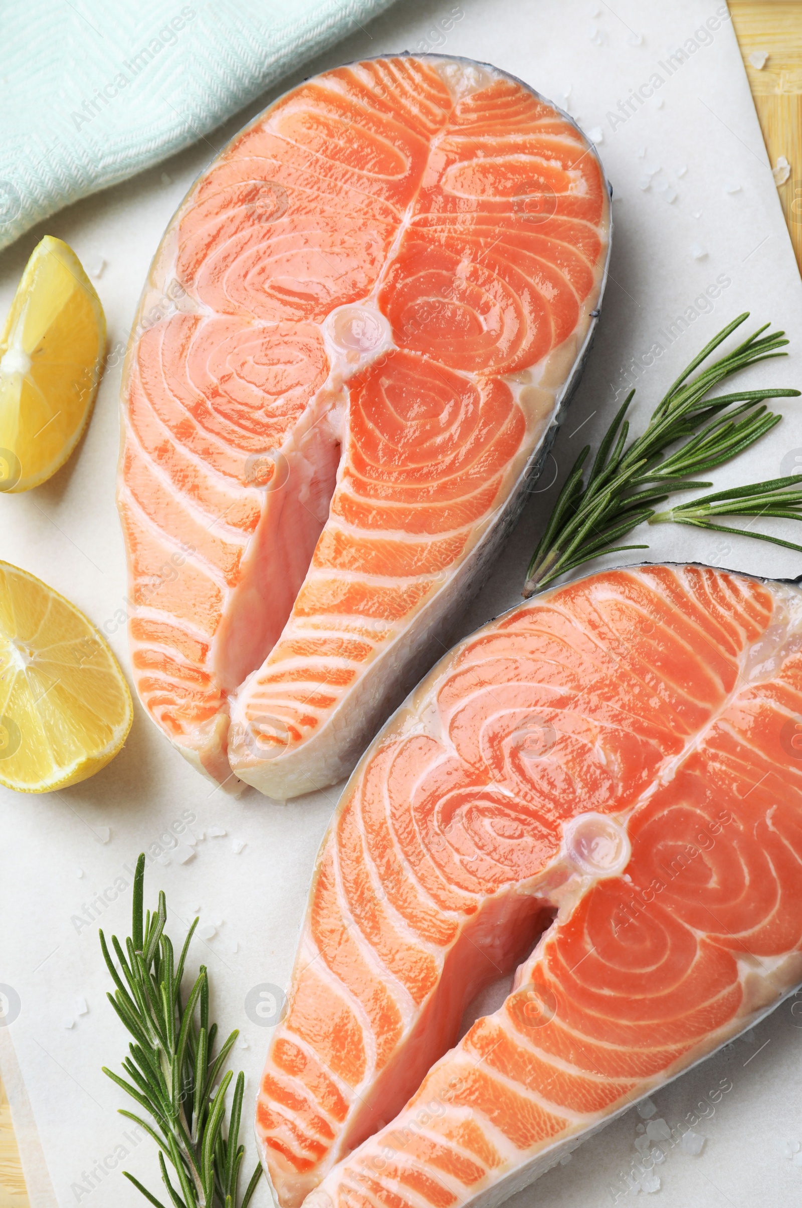Fresh raw salmon with lemon and rosemary on parchment, flat lay. Fish delicacy Photo of Fresh raw salmon with lemon and rosemary on parchment, flat lay. Fish delicacy