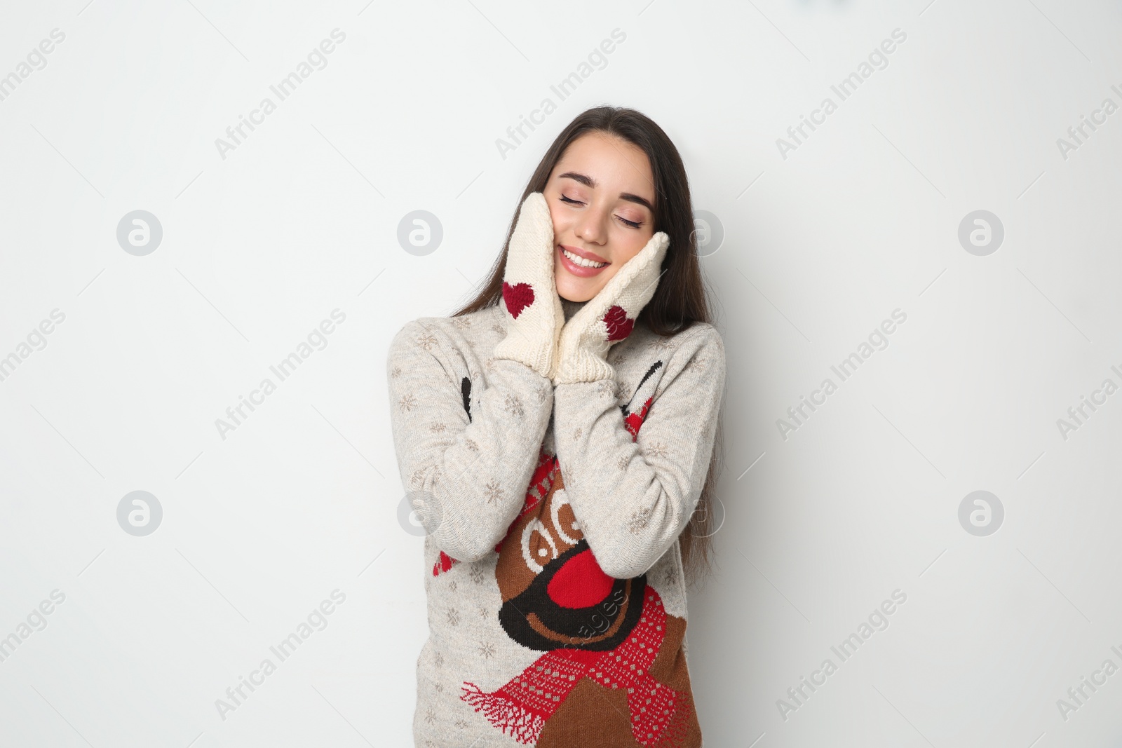 Young woman in Christmas sweater and mittens on white background Photo of Young woman in Christmas sweater and mittens on white background
