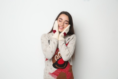 Young woman in Christmas sweater and mittens on white background Photo of Young woman in Christmas sweater and mittens on white background