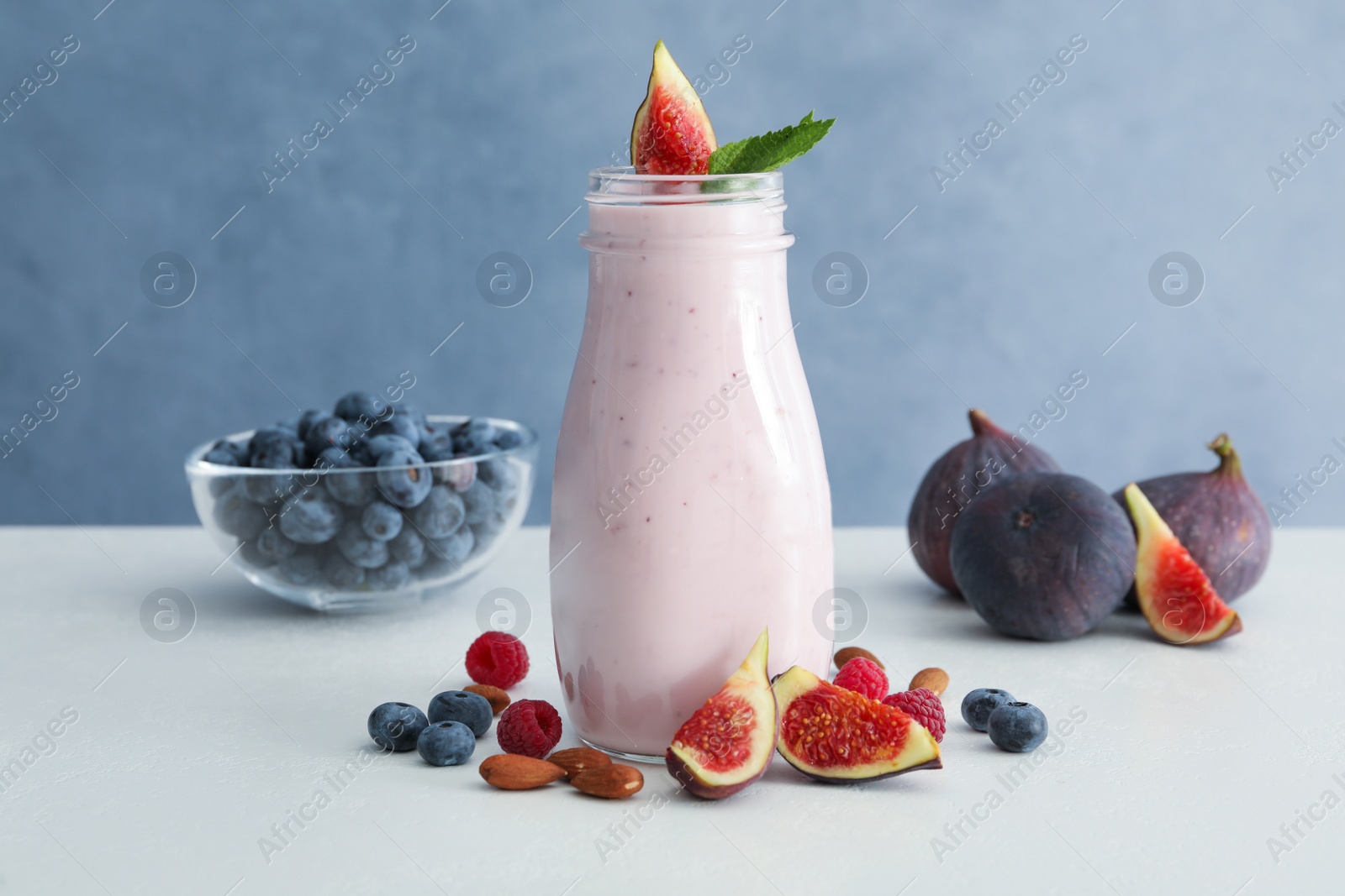 Delicious fig smoothie in glass bottle on white table Photo of Delicious fig smoothie in glass bottle on white table