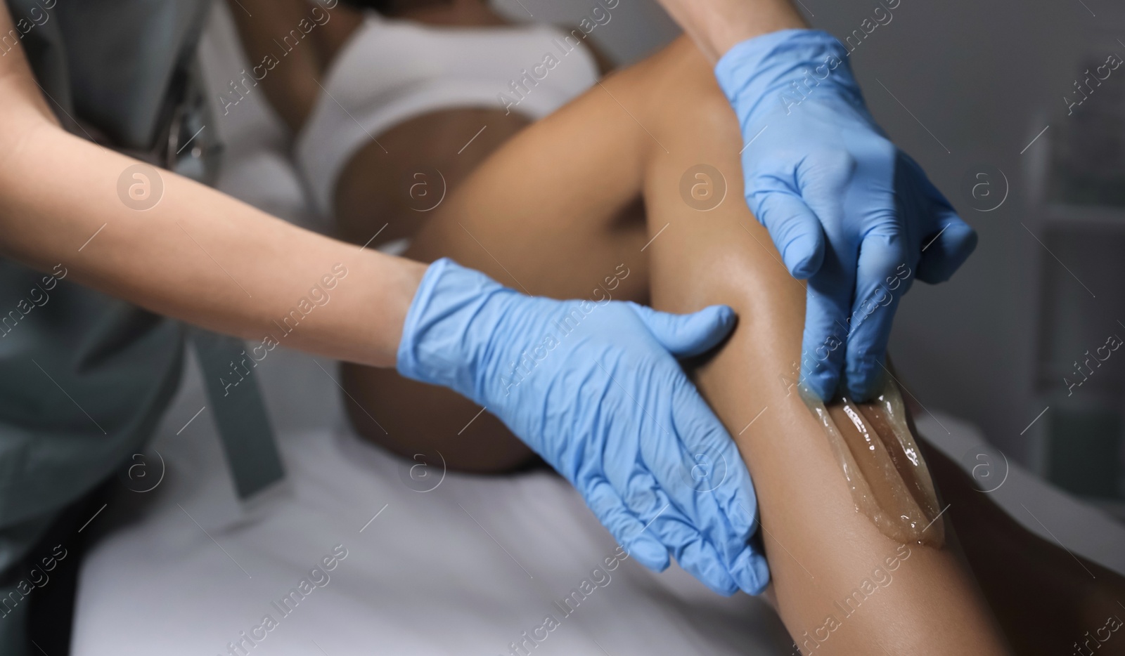 Young woman undergoing hair removal procedure on legs with sugaring paste in salon, closeup Photo of Young woman undergoing hair removal procedure on legs with sugaring paste in salon, closeup
