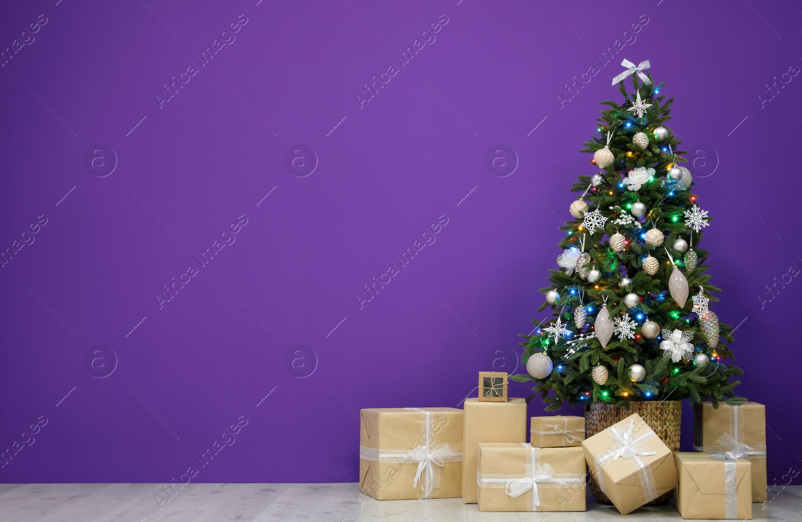 Beautiful Christmas tree and gift boxes near purple wall indoors, space for text Photo of Beautiful Christmas tree and gift boxes near purple wall indoors, space for text