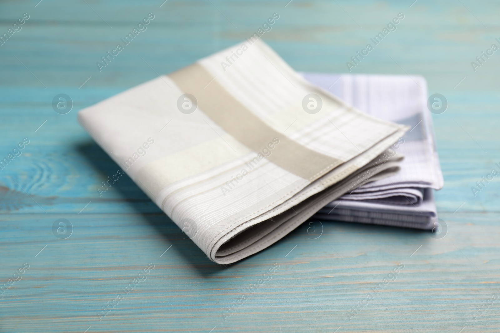 Stylish handkerchiefs on light blue wooden table Photo of Stylish handkerchiefs on light blue wooden table
