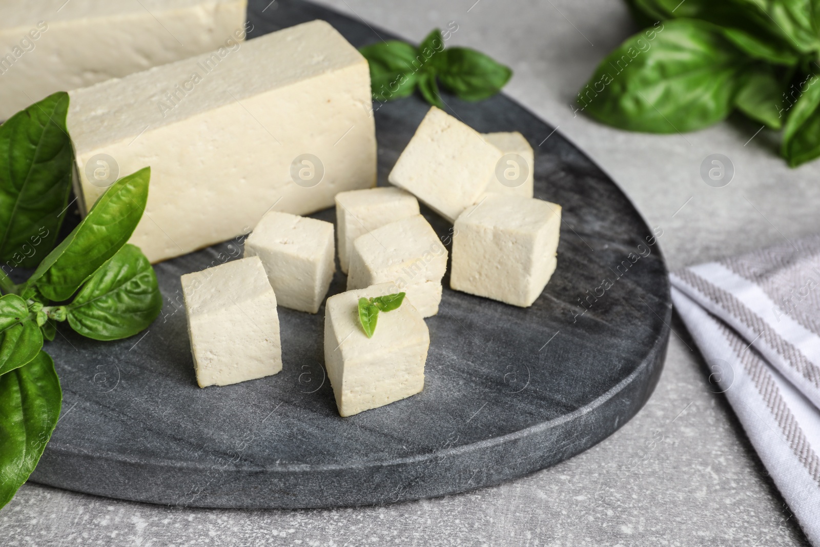 Delicious tofu with basil on grey table, closeup Photo of Delicious tofu with basil on grey table, closeup