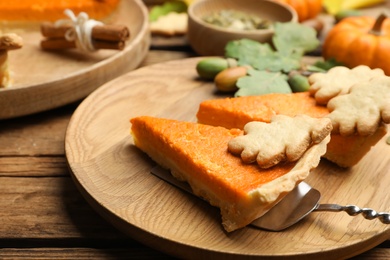 Slices of delicious homemade pumpkin pie on wooden plate, closeup Photo of Slices of delicious homemade pumpkin pie on wooden plate, closeup