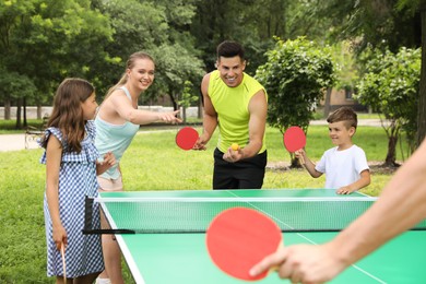 Happy family playing ping pong in park Photo of Happy family playing ping pong in park