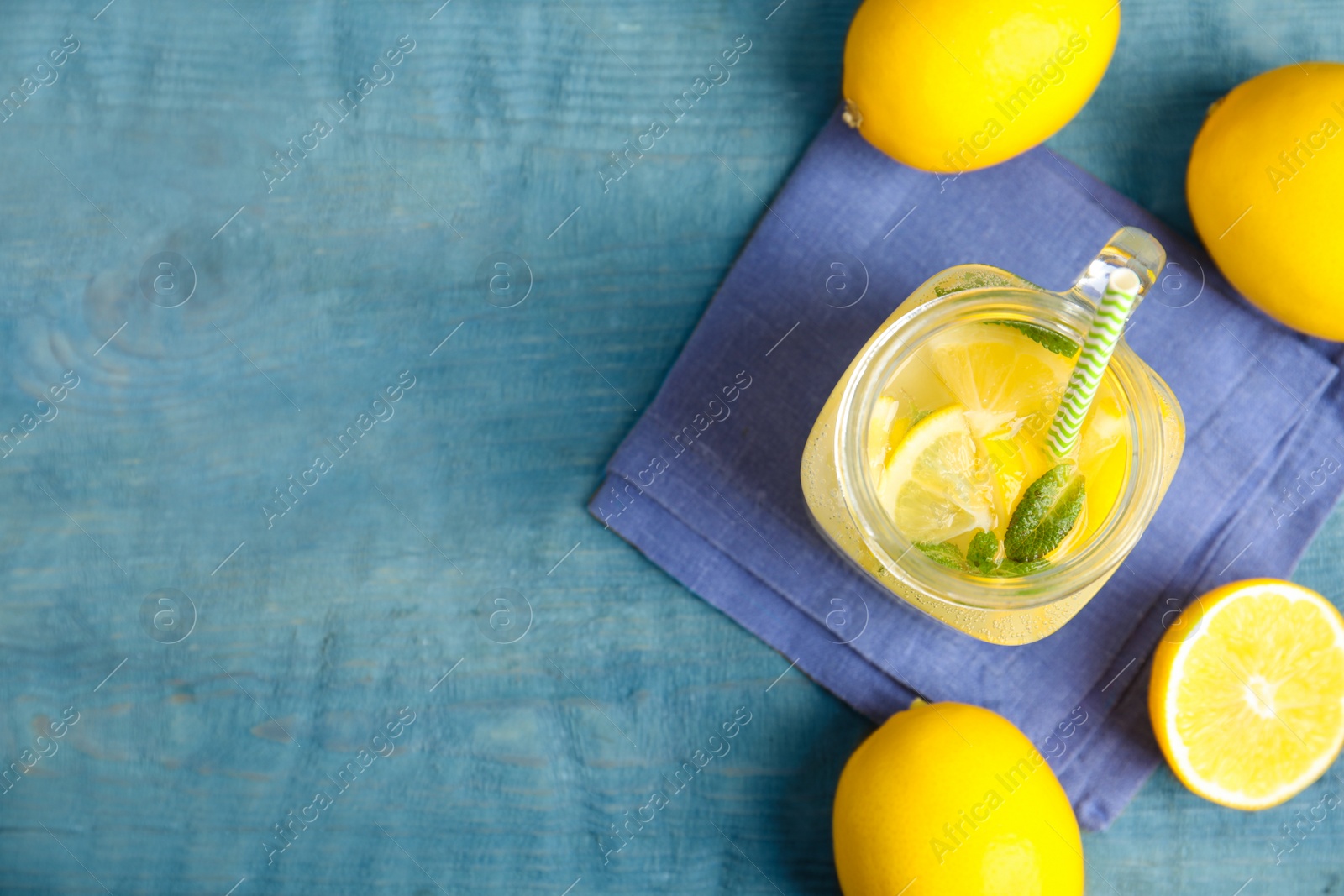 Photo of Cool freshly made lemonade and fruits on light blue wooden table, flat lay. Space for text