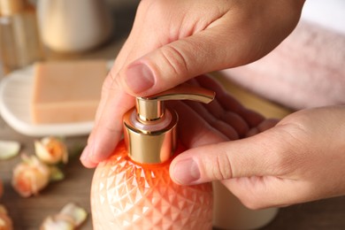 Woman using liquid soap dispenser, closeup view Photo of Woman using liquid soap dispenser, closeup view