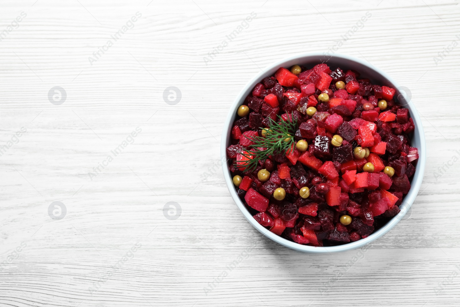 Traditional Russian salad vinaigrette on white wooden table, top view. Space for text Photo of Traditional Russian salad vinaigrette on white wooden table, top view. Space for text