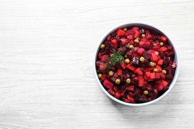 Traditional Russian salad vinaigrette on white wooden table, top view. Space for text Photo of Traditional Russian salad vinaigrette on white wooden table, top view. Space for text