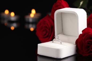 Beautiful engagement ring with gemstone in box and roses on black background. Space for text Photo of Beautiful engagement ring with gemstone in box and roses on black background. Space for text